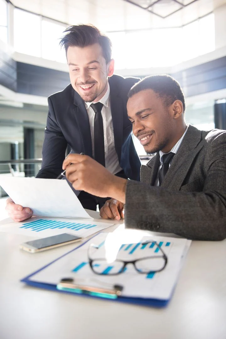 Dos personas revisando juntas un documento con gráficos